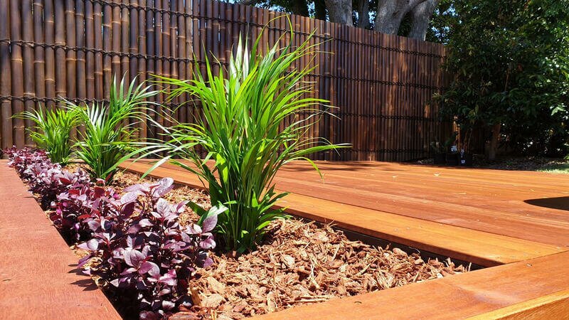 Hardwood deck framed by a mulched garden bed