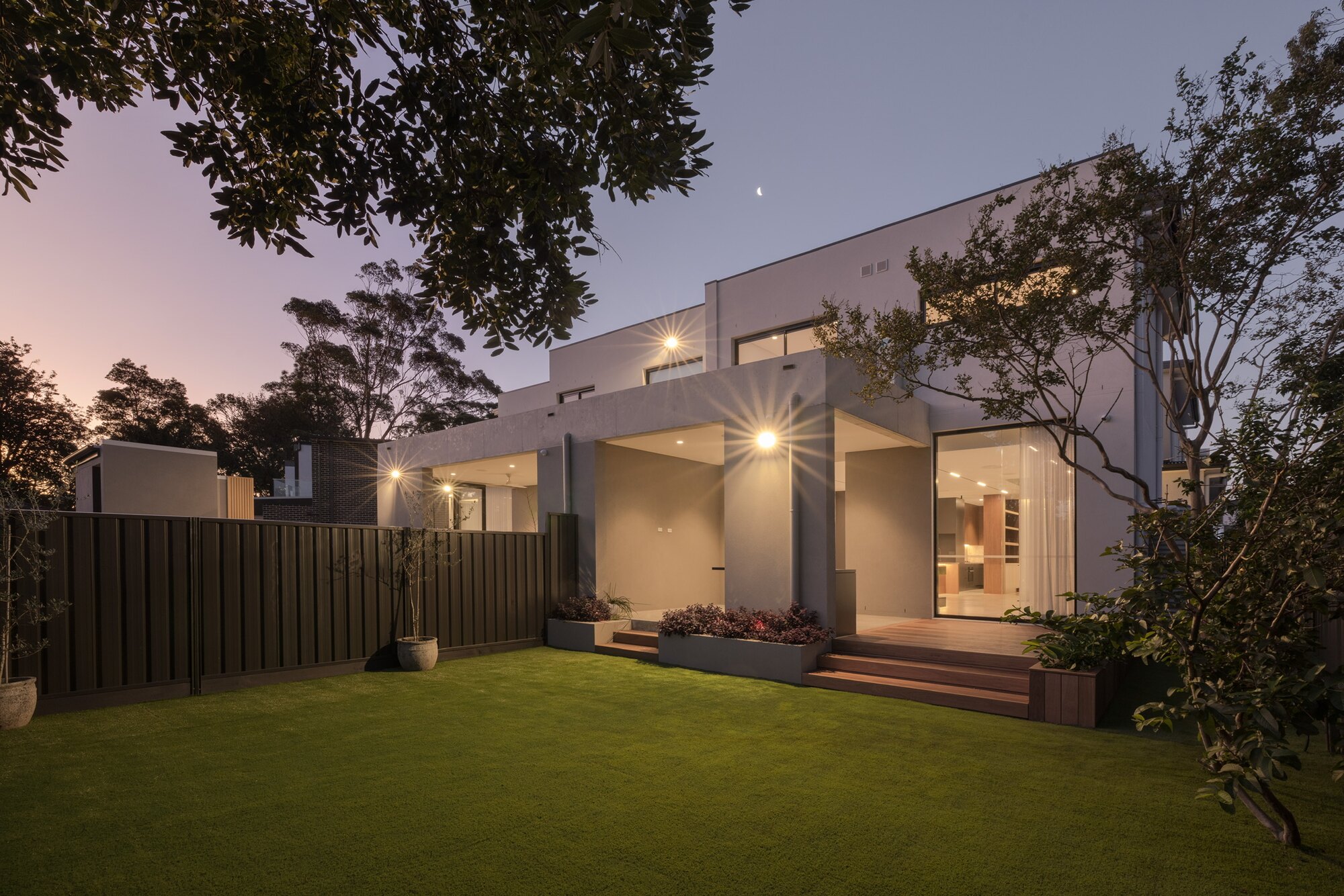 Modern backyard lawn and garden beds at dusk